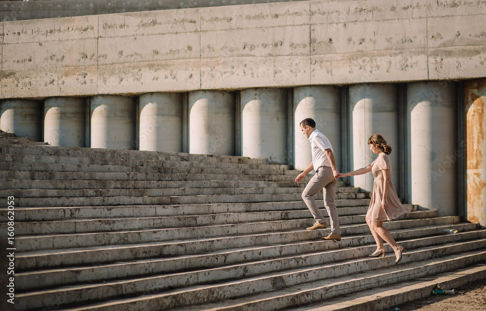 a beautiful couple, a girl with a guy in summer clothes, dress beige, running up the stairs a beautiful couple, a girl with a guy in summer clothes, dress beige, running up the stairs