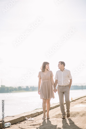the girl with the guy stand near the river facing each other in the summer clothes, the heat, the sun
