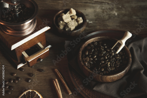 coffee grinder with beans and brown sugar in bowls on wooden tabletop