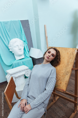 Woman leaning against an easle in an art room photo