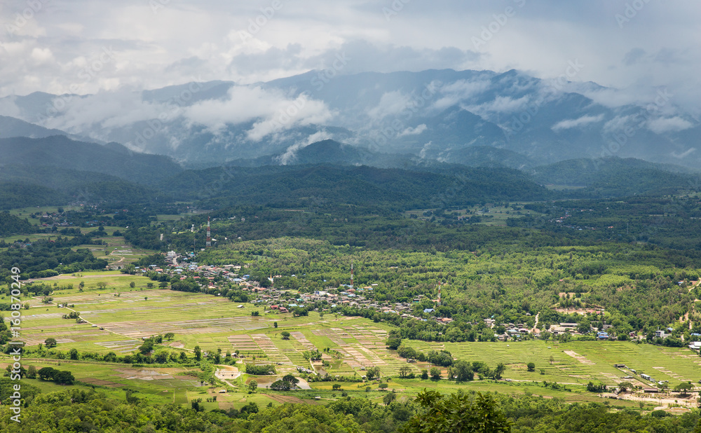 Obraz premium Panorama view of green land with sunlight and mountain covered by cloud and fog in countryside of Thailand on rainy season.