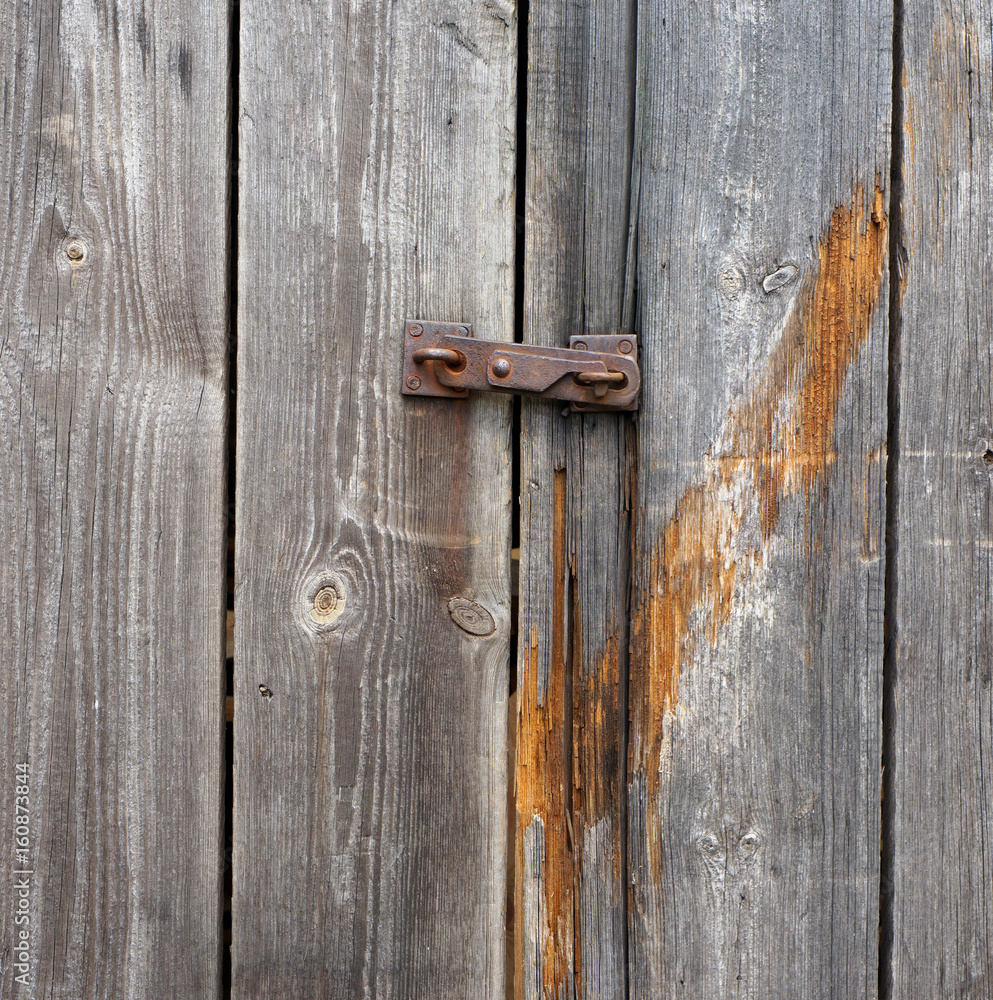 Small iron rusty latch on a mouldering wooden door Small iron rusty latch on a mouldering wooden door