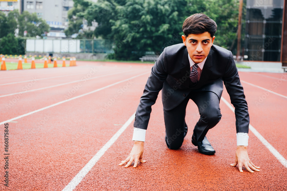Business man in suit starting and preparing to run on the competition running performance track Business man in suit starting and preparing to run on the competition running performance track