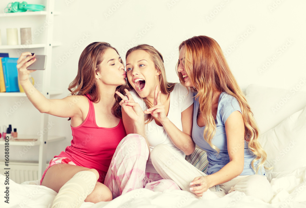 teen girls with smartphone taking selfie at home