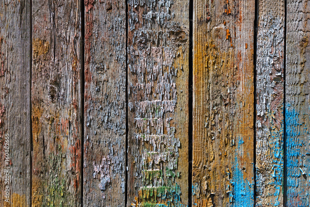 Fototapeta premium A wooden background with boards standing vertically painted with bright colors of different colors paint. Paint eventually peeled off