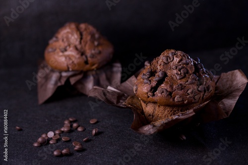 Two dark chocolate muffins with black background
