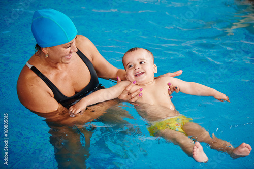 Healthy family, mother teaching baby swimming pool © amixstudio