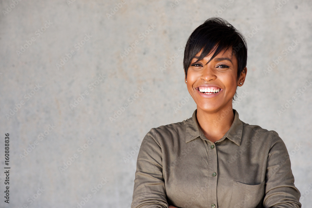 Close up beautiful young black woman smiling against gray wall Close up beautiful young black woman smiling against gray wall