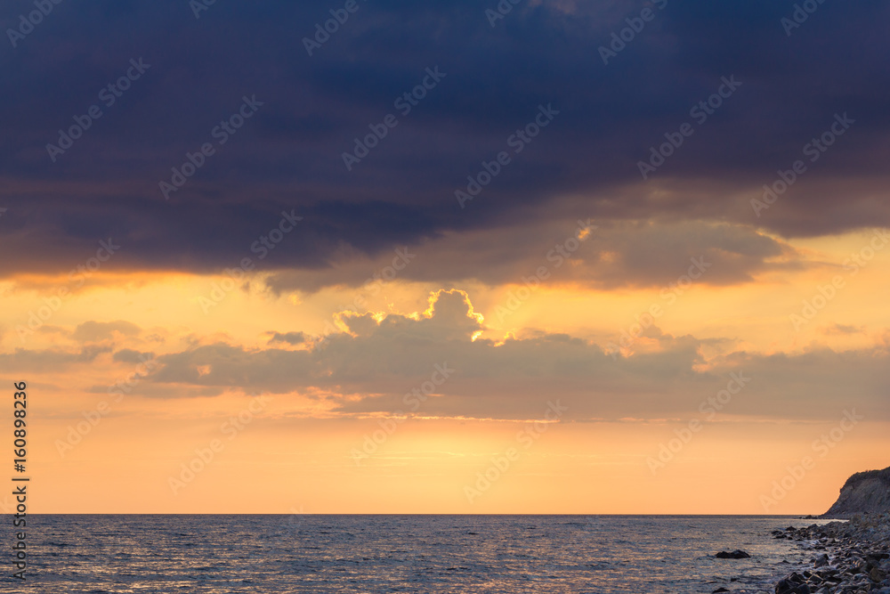 Beautiful sunset among the unimaginable clouds with glimpses of rays on the sea 