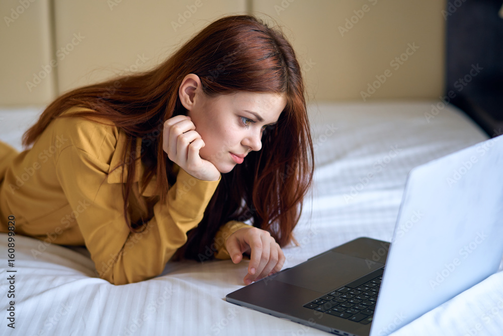 Woman working behind laptop, woman lying in bed Woman working behind laptop, woman lying in bed