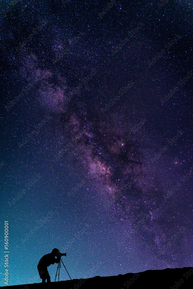 Naklejka premium Krajobraz z galaktyką Drogi Mlecznej. Nocne niebo z gwiazdami i sylwetką Fotograf robi zdjęcie na górze.