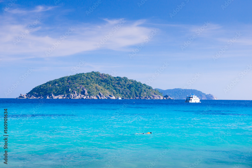 Naklejka premium A boat floating in turquoise sea in Summer at Similan island - Phang nga Thailand