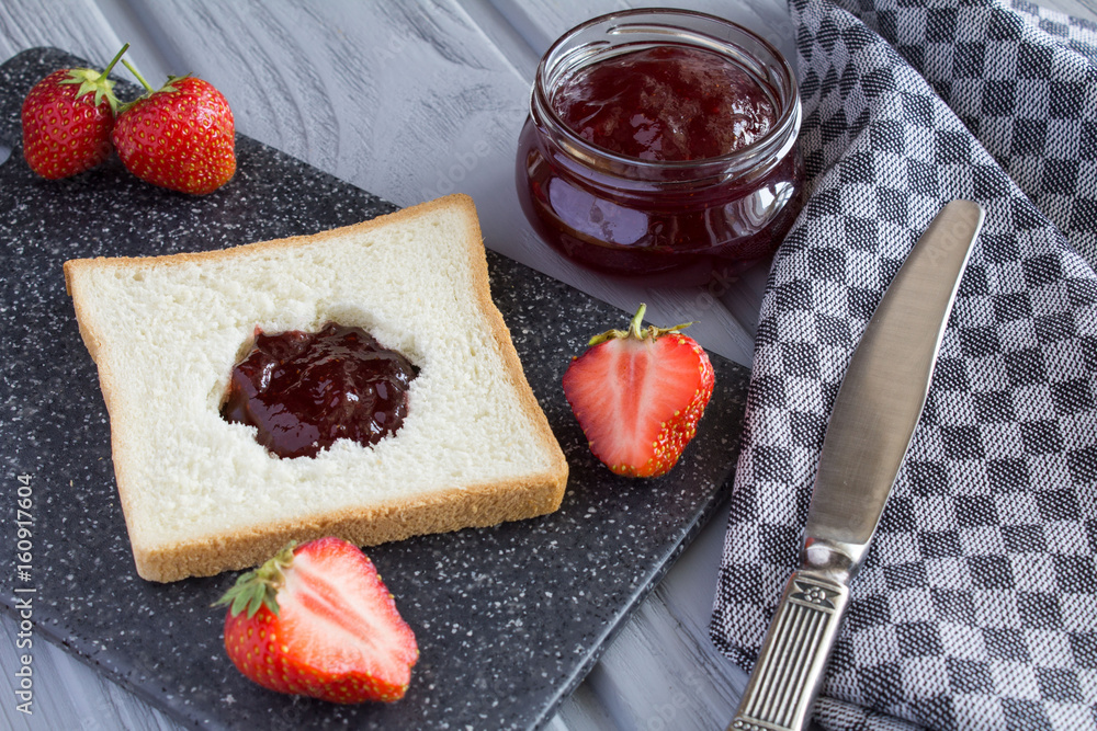 Bread toast with strawberry jam on the grey cutting board Bread toast with strawberry jam on the grey cutting board
