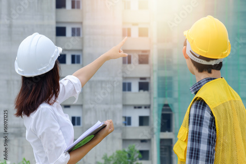 Woman engineer discussing building project with foreman and point finger to the site workplace, Engineer checking work for control on site concept