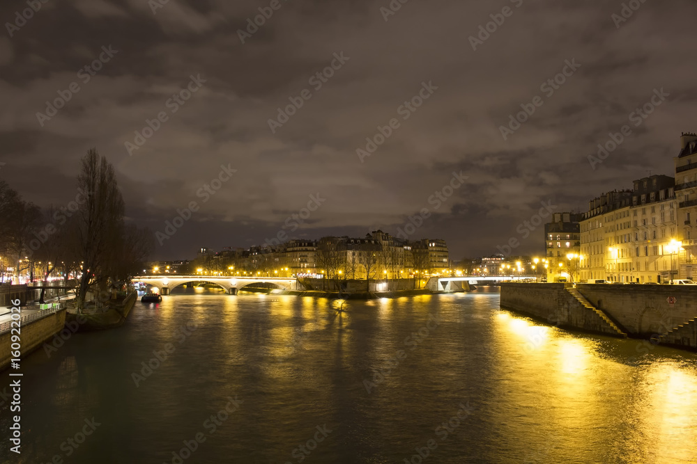 View of long exposed Seine river and historical architecture buildings in Paris at night in winter.