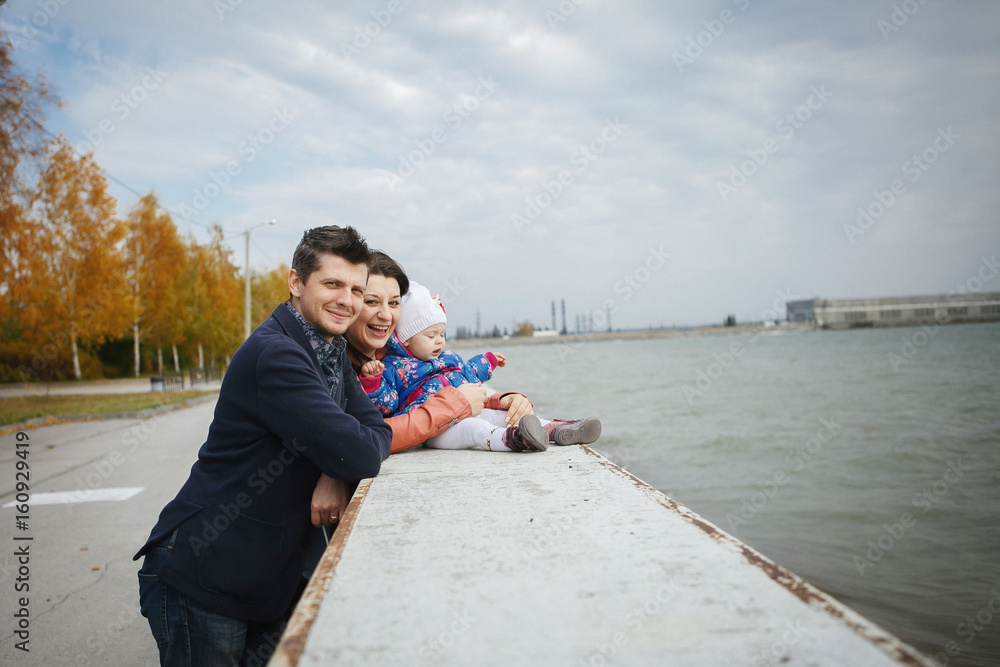 Happy young family walking in Park in autumn by the water on the shore