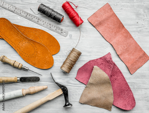 Working place of shoemaker. Skin and tools on grey wooden desk background top view photo