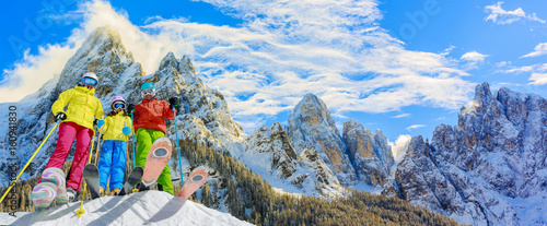 Skiing family enjoying winter vacation on snow in sunny cold day in mountains and fun. San Martino di Castrozza, Italy. photo