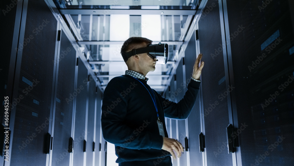 IT Engineer Wearing Virtual Reality Headset Works with Augmented Reality Software in Data Center. He Wirelessly Interacts with Rack Servers. IT Engineer Wearing Virtual Reality Headset Works with Augmented Reality Software in Data Center. He Wirelessly Interacts with Rack Servers.