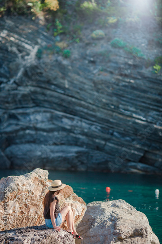 Young girl in a cove on a rock in the Cinque Terre reserve. Stunning nature and fresh air in the gulf