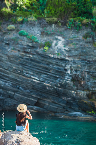Young girl in a cove on a rock in the Cinque Terre Reserve. Stunning nature and fresh air