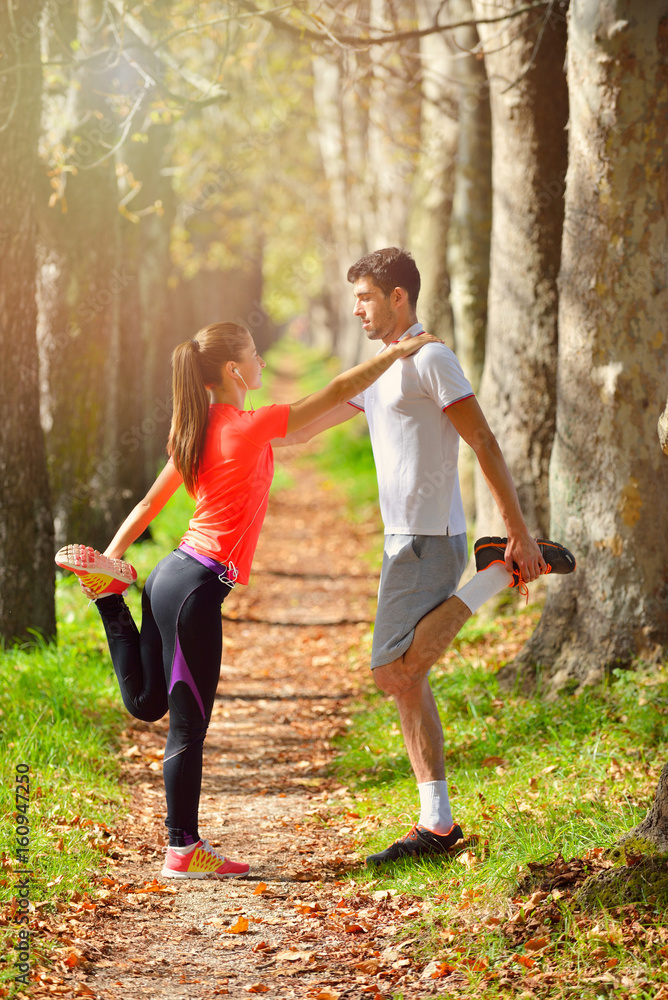 Fototapeta premium Young couple stretching legs before running in autumn nature