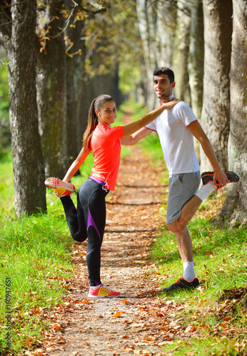 Fototapeta Naklejka Na Ścianę i Meble -  Young couple stretching legs before running in autumn nature