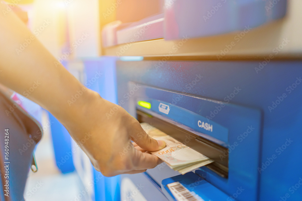 woman hand withdrawing money from indoor bank ATM,hand getting thai baht banknotes .selective focus,vintage color woman hand withdrawing money from indoor bank ATM,hand getting thai baht banknotes .selective focus,vintage color