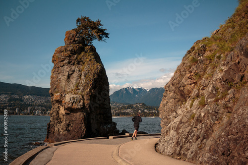 Photo of runner passing through Siwash rock at Stanley Park, Vancouver, BC