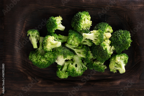 Bunch of boiled green broccoli on brown plate over wooden background