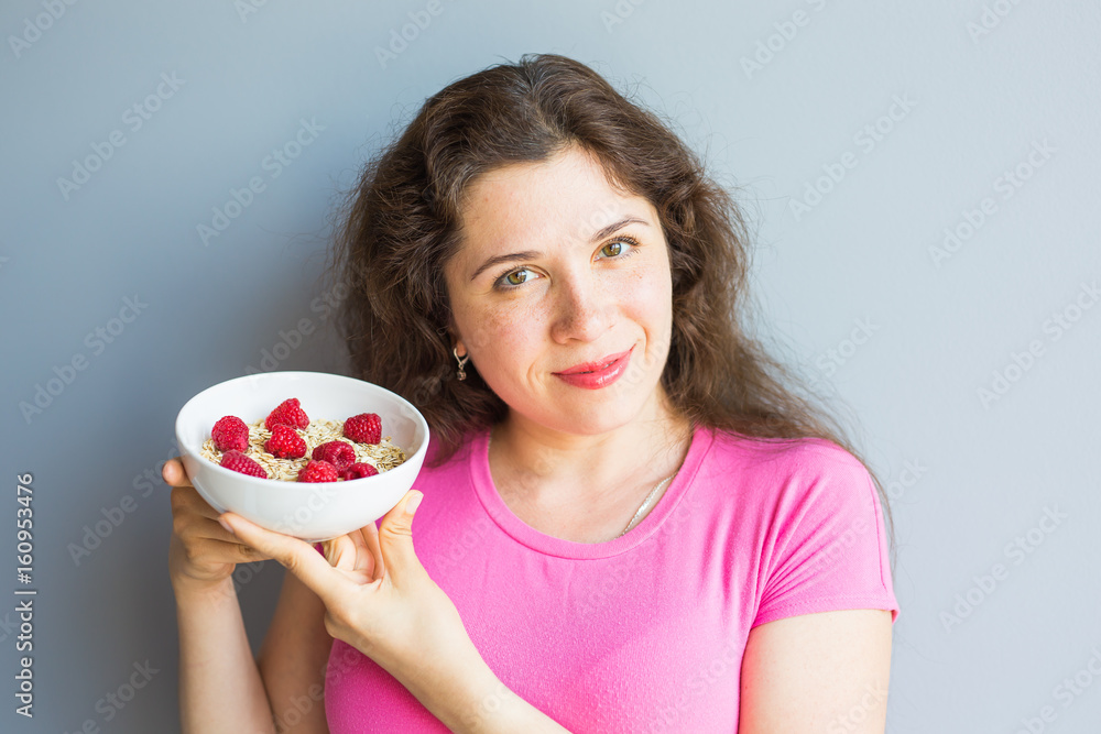 Smiling woman hold healthy and natural breakfast, oatmeal and raspberries in a bowl Smiling woman hold healthy and natural breakfast, oatmeal and raspberries in a bowl