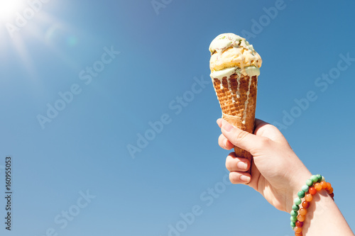 Hand holding ice cream cone on the sky background