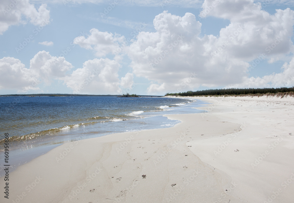 white sandy beach in nova scotia with blue sky and clouds