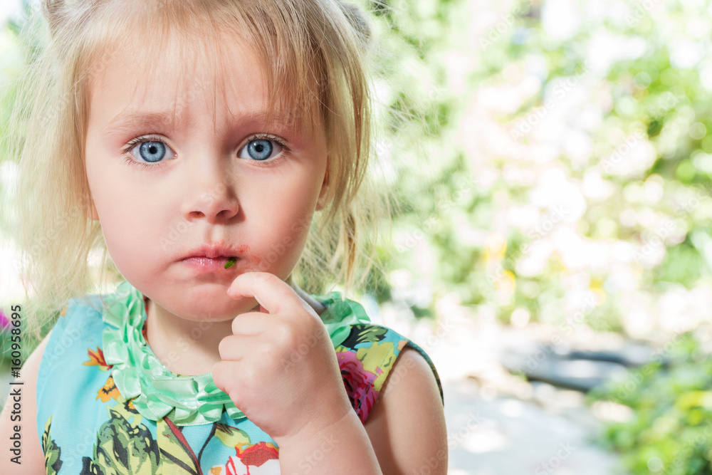 Child, little girl ate a strawberry and smeared her lips, close-up portrait Child, little girl ate a strawberry and smeared her lips, close-up portrait