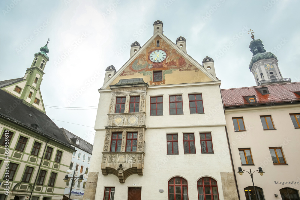 A low angle view of the town hall with clock and Saint Georges Church belfry at town square in Freising, Germany.