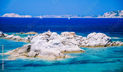 Granite rocks in sea, amazing azure water, white sailboats in background near Porto Pollo, Sardinia, Italy photo
