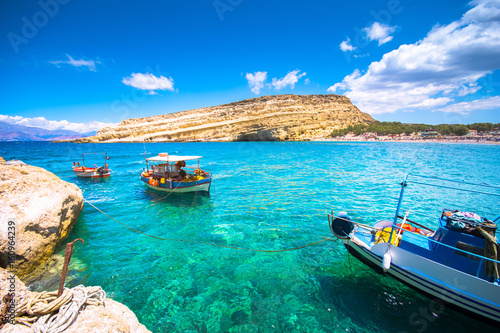 Fototapeta Naklejka Na Ścianę i Meble -  Matala beach with old fishing boats and caves on the rocks that were used as a roman cemetery and at the decade of 70's were living hippies from all over the world, Crete, Greece