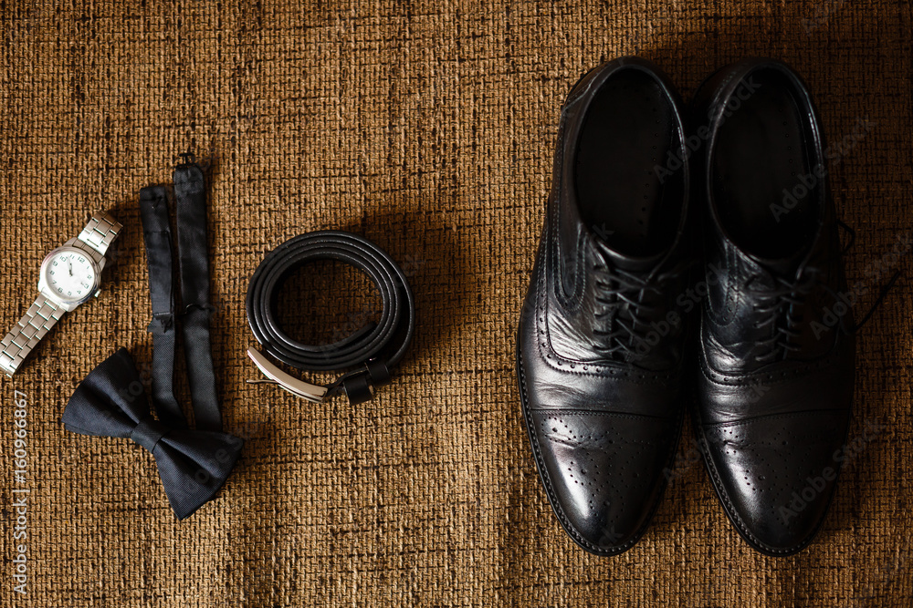 black shoes, black belt, black watch, black butterfly, cufflinks and perfume on a brown background with sacking black shoes, black belt, black watch, black butterfly, cufflinks and perfume on a brown background with sacking