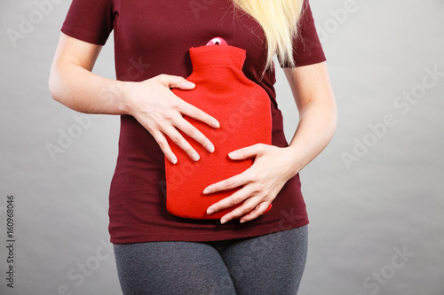 Girl having stomach ache, holding hot water bottle