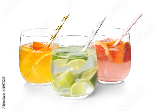 Tasty refreshing lemonade with different fruits in glasses on white background