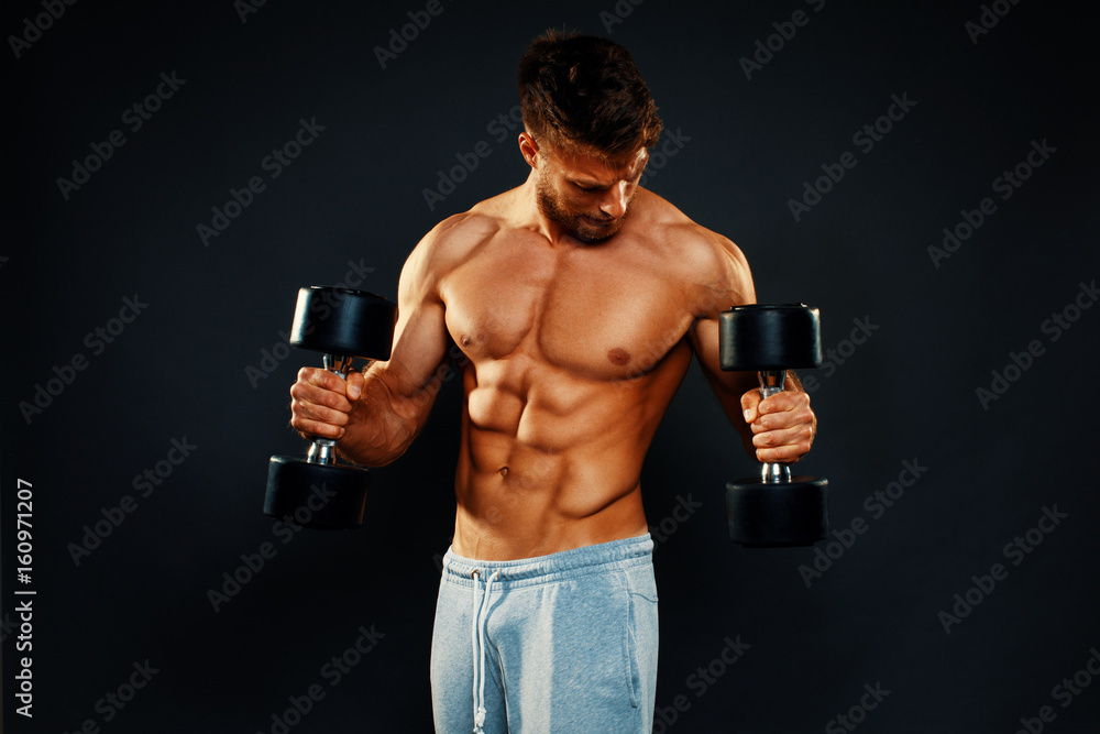 Attractive fitness man holding dumbbells in the hands in studio
