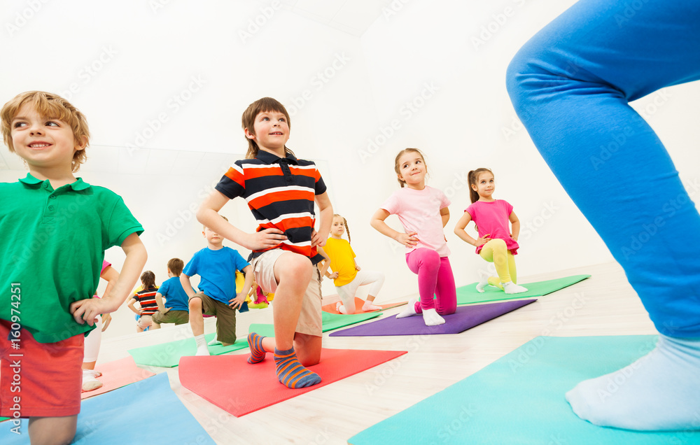Kids doing knee bending exercises at gym lesson