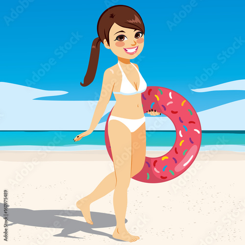 Beautiful young woman walking on the beach with doughnut inflatable wearing white bikini