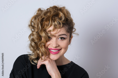 Young woman with curly hair, smiling and looking at camera