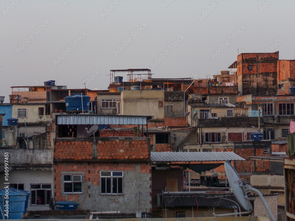 Group of houses calls Favela at Rio de Janeiro Cityscape during day - with blue sky and white clouds. Favela Portuguese for slum, is a low-income historically informal urban area in Brazil.