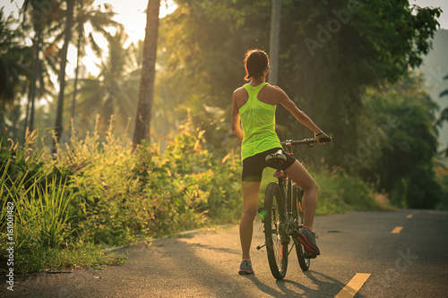 Young woman cyclist cycling on tropical forest trail
