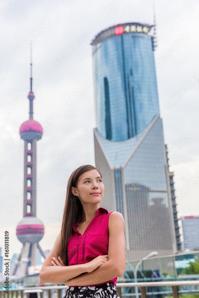 Chinese young professional in Shanghai city center. Business woman in Pudong financial district and tower. Proud confident successful corporate executive or Asian multiracial businesswoman in China.