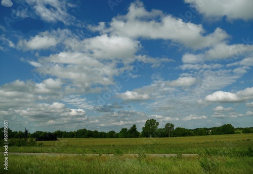 Beautiful cotton clouds hang above a green countryside 
