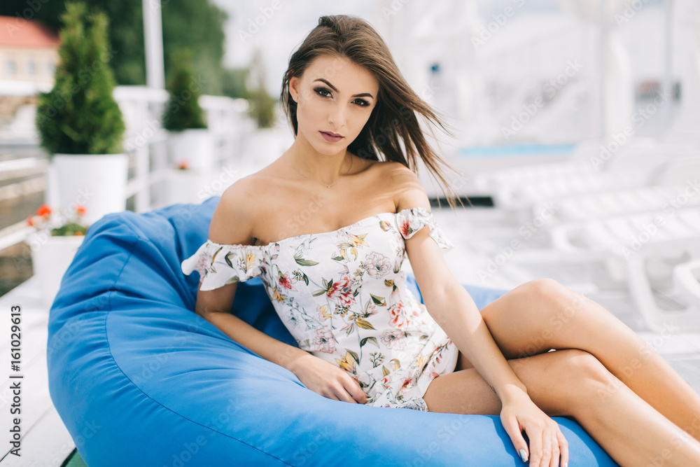 Portrait of a beautiful woman in a dress posing on a white wooden beach of summer.