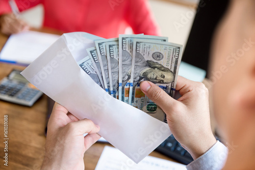 Businessman checking money inside the envelope at his working desk